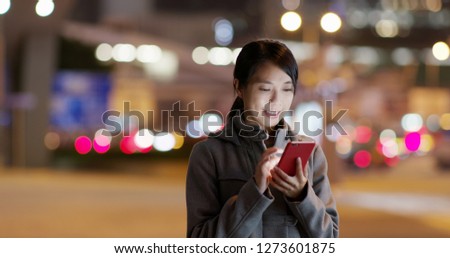 Woman look at the cellphone and searching for location in the the street at night