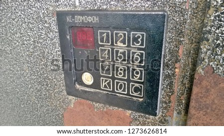 Texture, background, wallpaper of the intercom and its dial on the old gray-black metal surface, walls, entrance doors. The word "intercom" in Russian.
