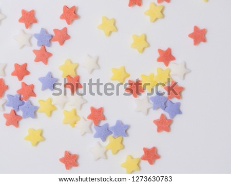 Star shaped sugar sprinkles(cookie icing) with various colors(living coral, blue, yellow and white, pink, ginger) on white background