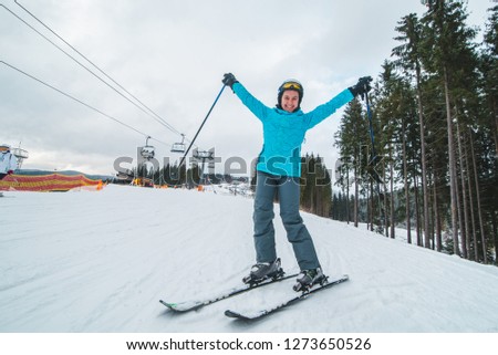 wide angel picture of skiing smiling young adult woman. lift on background