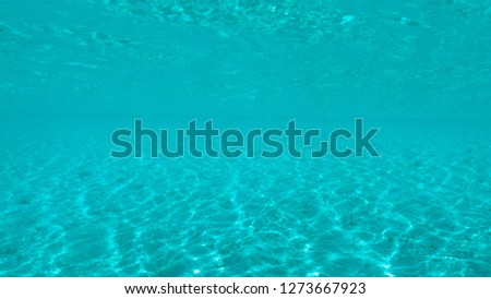 UNDERWATER: Bright tropical sun rays shine through the tranquil surface of the serene blue ocean. Breathtaking underwater view of the empty sandy ocean floor in the middle of the endless Pacific.