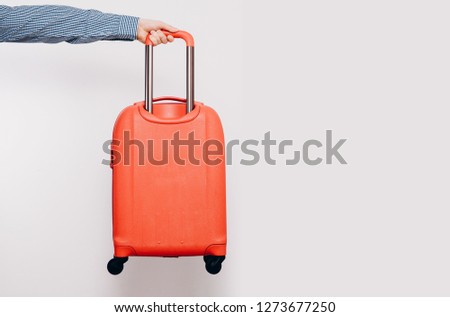 The man is giving by hand A red travel suitcase on wheels, isolated on a white background. Travel concept, packing up before departure. Preparing for travel, going on vacation, break, rest.