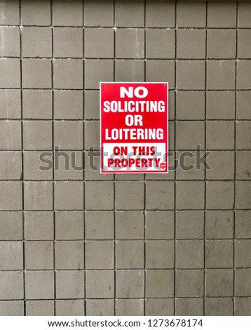 No soliciting or loitering sign hanging on a wall outside of a retail store