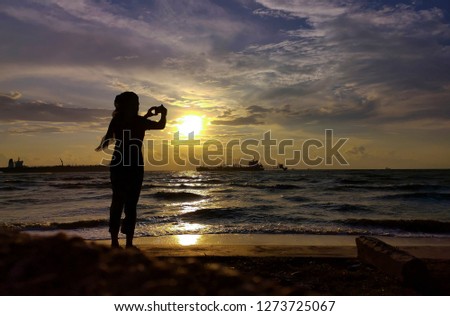 PORT DICKSON, MALAYSIA : Silhouette. A woman on the beach by taking pictures of beautiful scenery on January 02, 2019