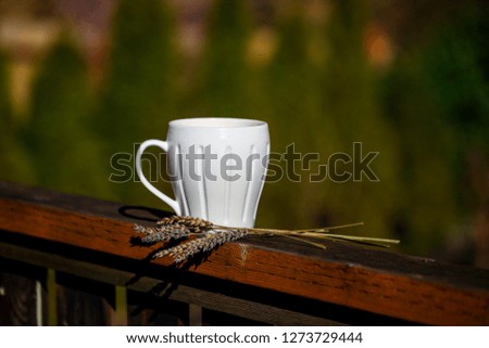 Close up white cup of hot coffee on balcony edge with natural background 