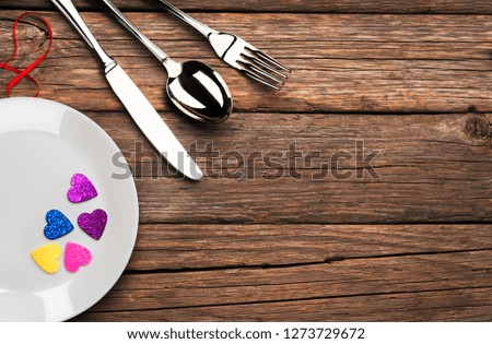Valentine's Day, colored hearts and cutlery on old wooden table