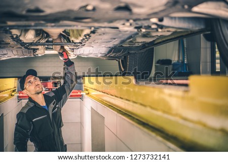 Vehicle Diagnostic Station. Caucasian Auto Service Worker Checking Car Under Carriage Looking For Potential Issues. Royalty-Free Stock Photo #1273732141