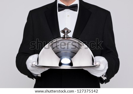 Waiter serving a meal under a silver cloche or dome Royalty-Free Stock Photo #127375142