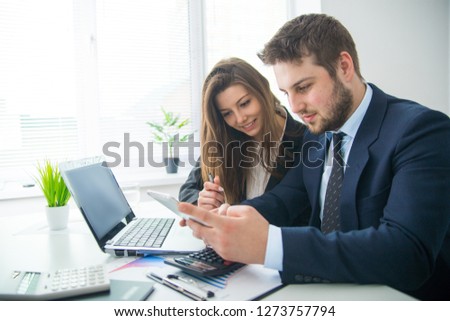 Young businessman discussing something with his colleague, and using a digital tablet together
