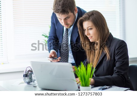 Young businessman discussing something with his colleague, and using a digital laptop together