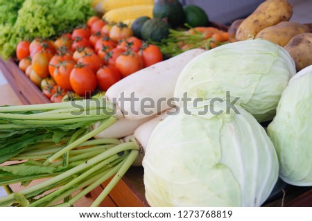 Pictures of various fruits placed in wooden crates such as tomatoes, corn, avocado, carrots, potatoes, cabbage and lettuce.