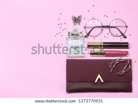 Colorful women's cosmetic set: glass, perfume, handbag, mascara and lip gloss on pink background with place for text, flat.