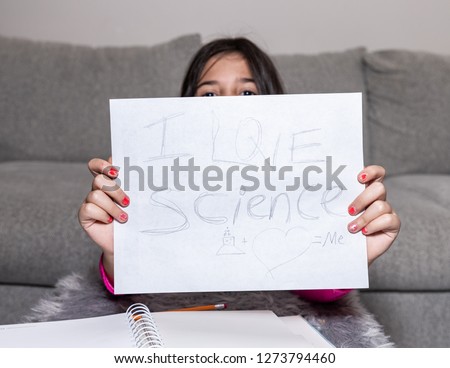 A young girl is showing a sign saying stating "I Love Science"