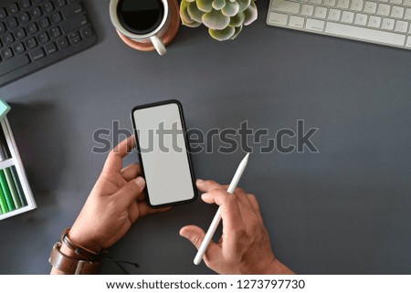 Graphic designer holding mobile smart phone on studio top table