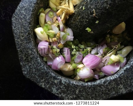 Top view picture of Thai herbs consist of shallot, galangal, garlic and coriander root on the mortar.