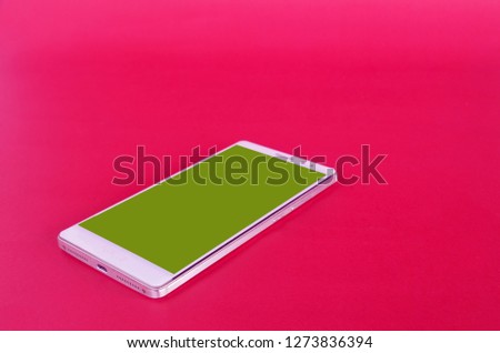 A green screen smartphone is placed on a pink background 