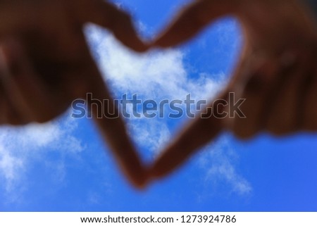 hands making a heart shape with blur blue sky. Love concept