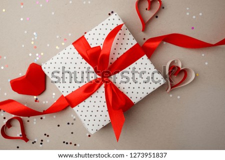 Valentines day concept with red origami paper hearts, confetti and gift box on gray background, romantic concept