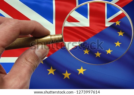 Hand with magnifying glass in search of the Brexit solution.