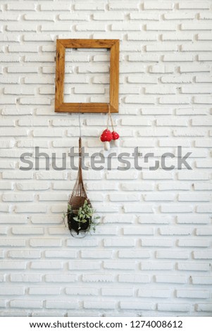 Wall of white bricks next to a plant in the pot and wood frame.