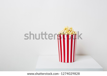 Full of popcorn in classic striped box on white background