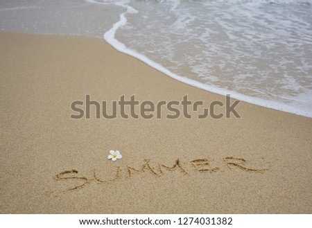 Summer written on the sand of beach with plumeria flower
