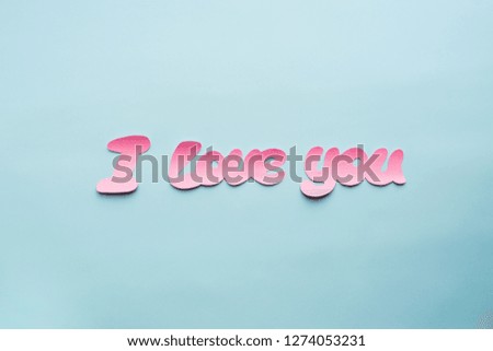 Words I love you cartoon style from pink paper on blue background. Valentine day minimal concept Flat lay Top view