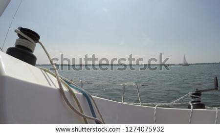 Picture aboard small recreational sailing boat with two modern self-tailing winches on here the line winched is a jib also showing lake horizon in background beautiful summer day