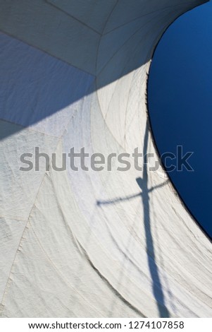 interplay of shadow and light on a white sail canvas as pictured with blue sky in the background