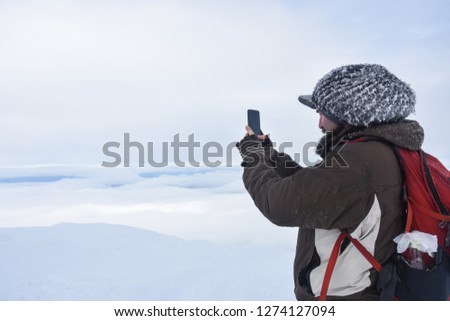 Hiker  taking picture of snowy mountain with a smart phone. Winter mountain landscape, Happy tourist hiking in winter 