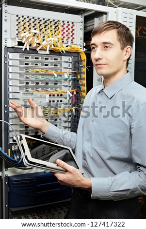 Let me show. The telecom engineer stand in data center and show telecommunication equipment