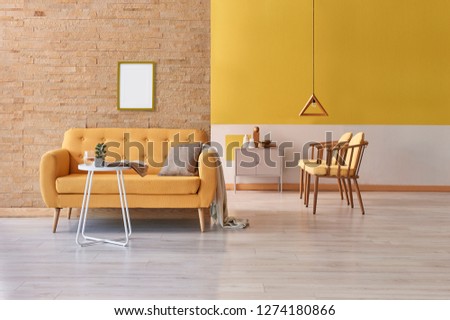 Yellow room, yellow sofa frame and picture decor, coffee table, and wooden lamp decor.
