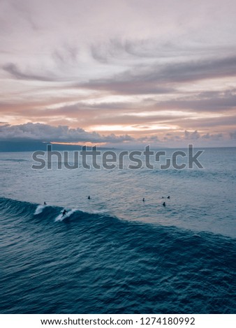 surfer riding a wave in Maui, Hawaii while sunset