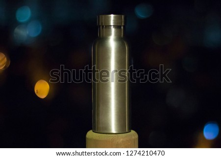 an insulated stainless steel bottle at the forest in the night