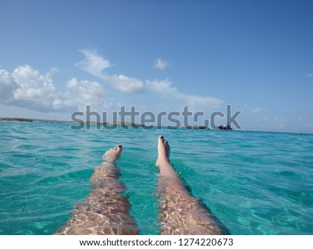 The legs of young woman floating on transparent blue sea with blue sky. Summer vacation at Ibiza paradise beach - Spain