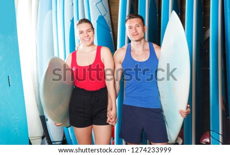 happy young sporty couple with surf equipment in surf club