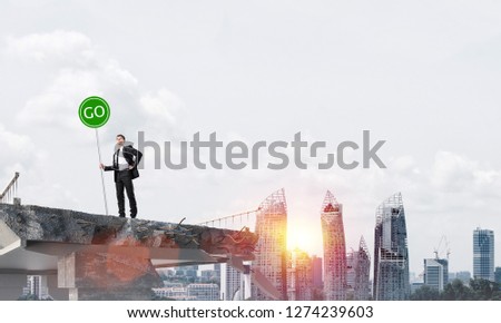Confident businessman in suit holding green go sign while standing on broken bridge with cityscape and sunlight on background. 3D rendering.