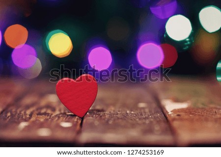 Red heart on the wood table and festive background with light spots and bokeh 