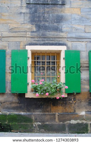 The photo was taken in the German city of Bayreuth. The picture shows a traditional window with flowers in an old house.