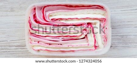Ice cream in a plastic box on a white wooden background, overhead view. Top view, from above.