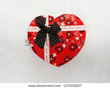 Red heart-shaped gift box on a white wood background