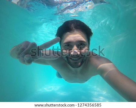 Young man underwater with peace sign