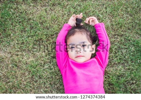happy little girl lying on green grass and playing in the park. soft focus.