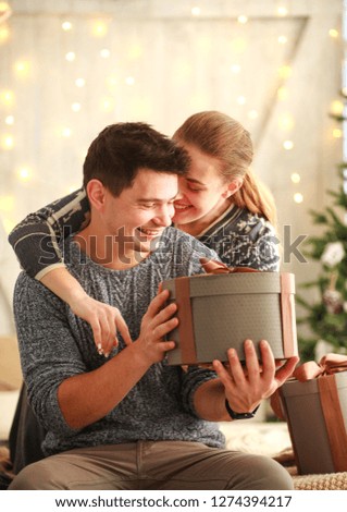 Happy young couple in love give gifts present in holiday at home