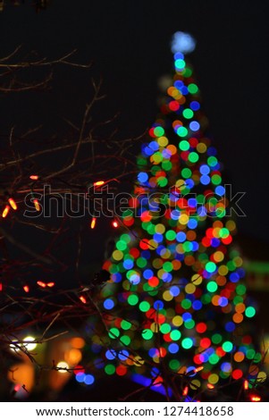 Christmas lights in focus with a blurry Christmas tree in the background