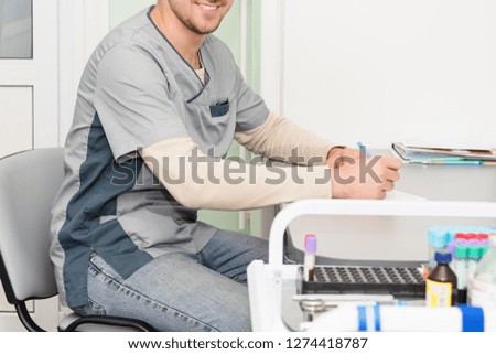 Doctor working, writing on paperwork. Modern hospital background.