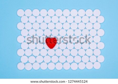 Global healthcare concept. Little red heart. Background of white pills macro with a red heart lying on a blue background, top view.