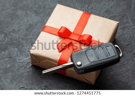 Gift box with car keys with remote control alarm system with red ribbon bow