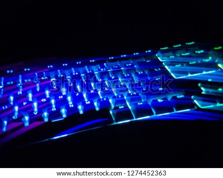 Light trail from RGB Gaming keyboard in a dark room with colorful LED backlit. Slight out of focus and motion blur was intentional.