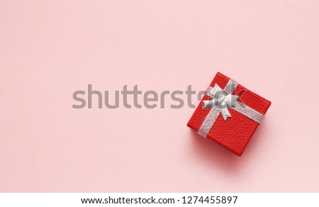 Red gift box on pink background. Festive texture. Happy Holiday.